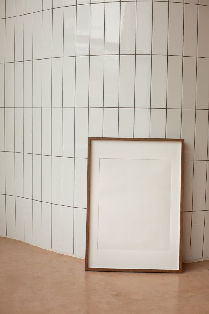 A minimalist interior featuring a blank vertical frame against tiled wall, offering ample copy space.